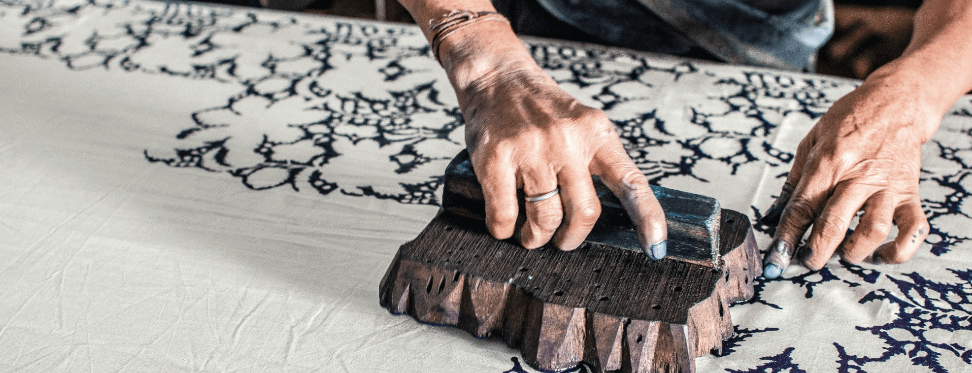 A person creating a floral print on a fabric using block printing method